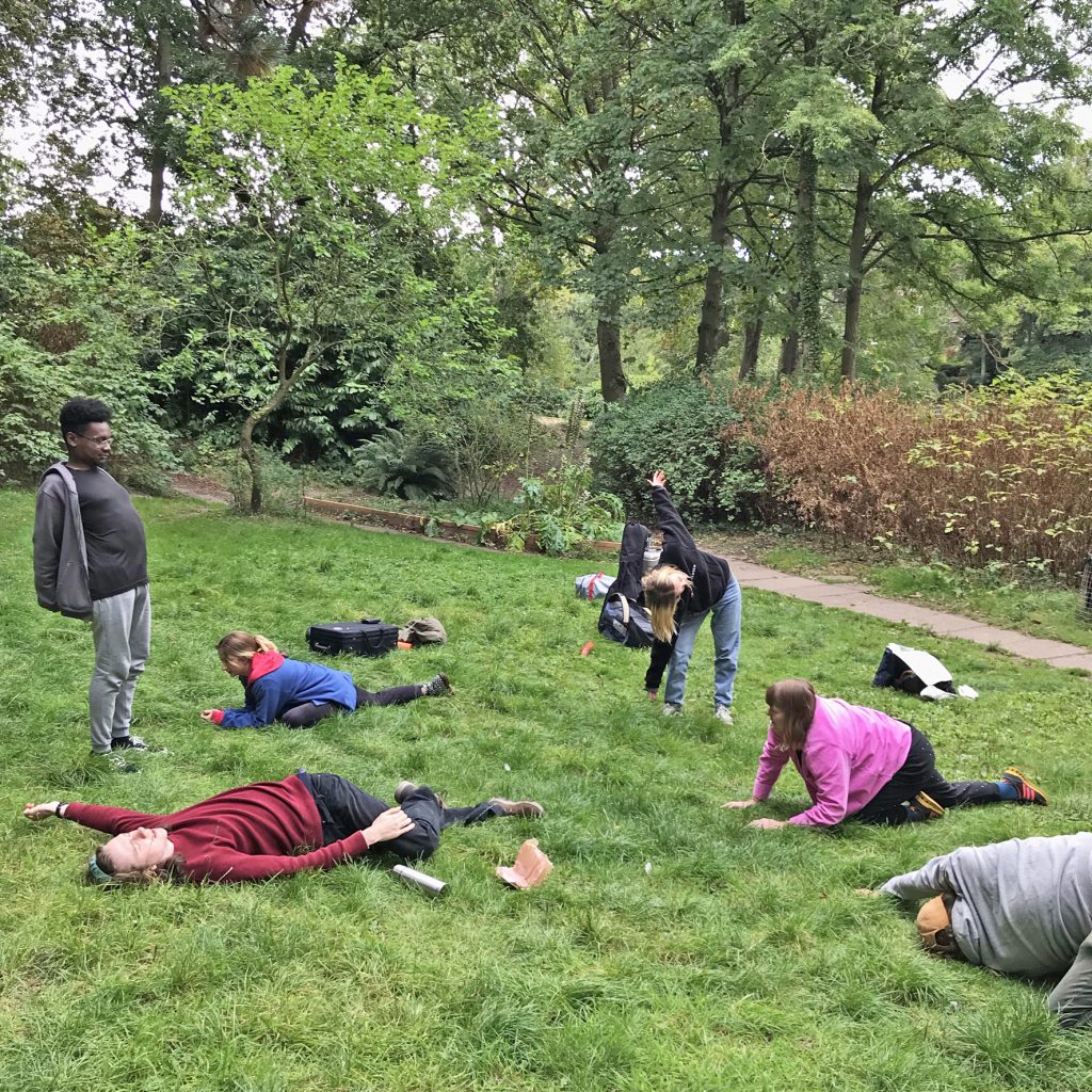 A photo of a group of young people doing stretches on the grass alongside the pool