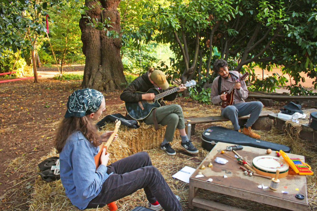 Three young people of varied ethnicities play music in the park
