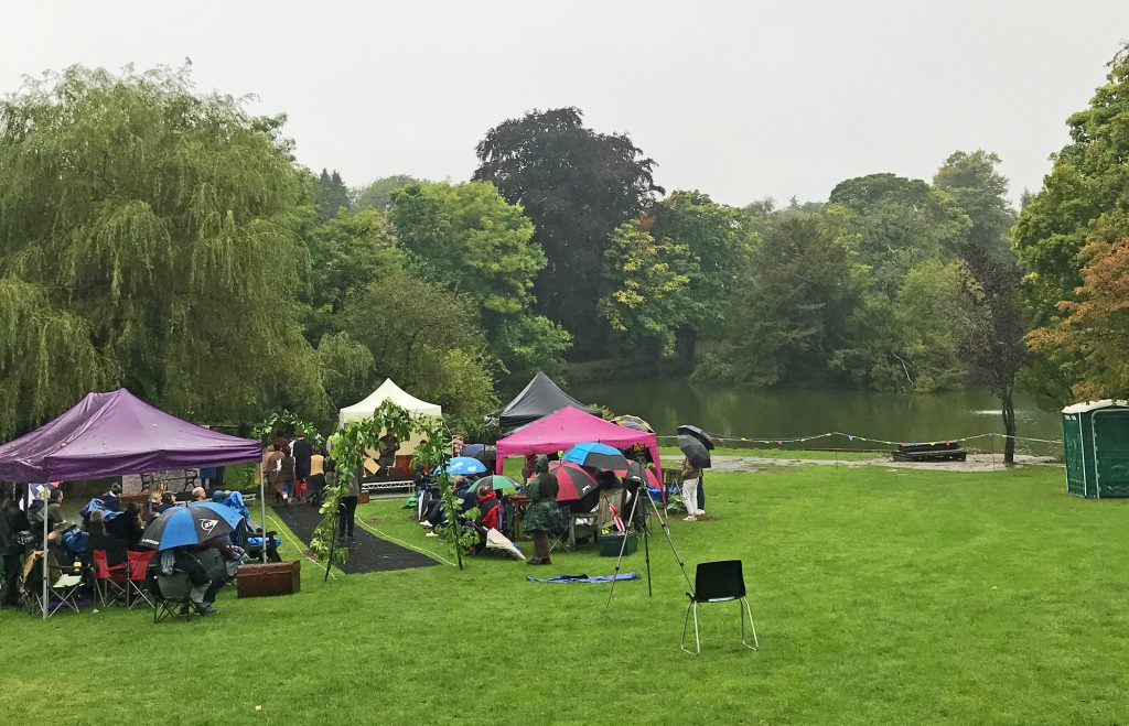 A photo of a performance of The Railway Children taking place near the pool in the rain