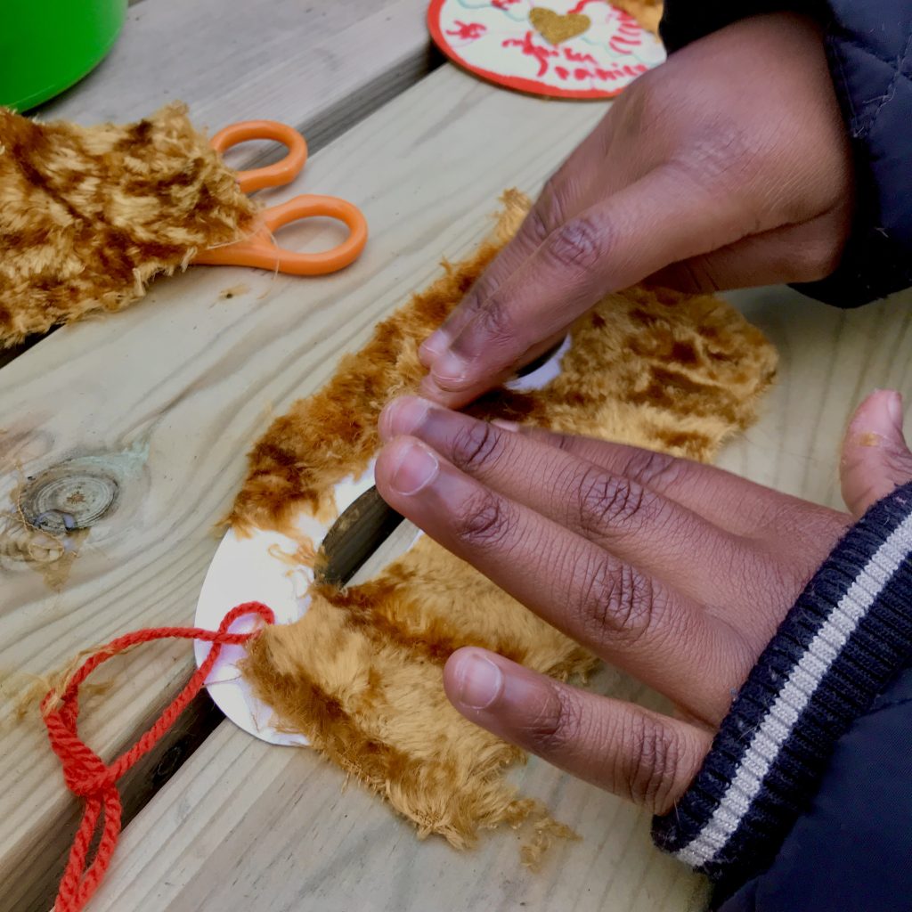 A photo of a child's hands glueing gold velvet on a mask
